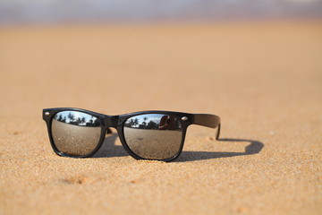 Mirrored safety glasses lie on the sand of a beach against the background  ocean.