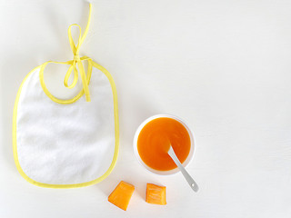 Bib, baby puree, spoon, Apple. The view from the top, flat lay.The concept of healthy nutrition for children.