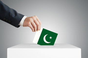 Man putting a voting ballot into a box with Pakistan flag.