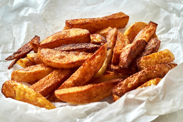 Tasty homemade potato french fries on white paper background