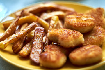 Tasty homemade potato french fries with chiken nuggets on yellow dish