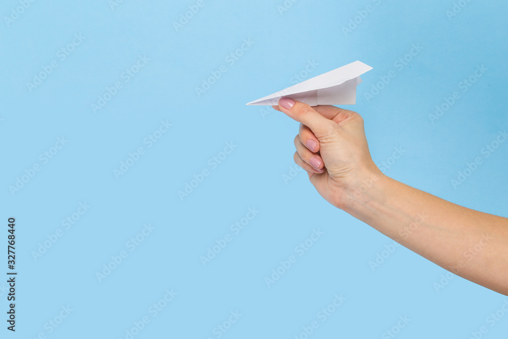 Wall mural Hands holding the sign of paper airplane or message on blue studio background. Negative space, advertising. Social media, showing meaning, communication, gadgets, modern technologies.