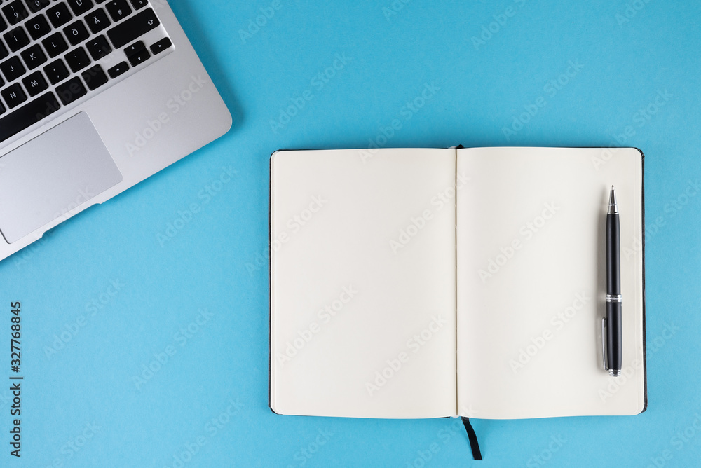 Wall mural open diary or notebook with blank white pages and laptop computer on blue background template