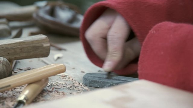 The guy sharpens a chisel for cutting wood on a grindstone manually. Close-up