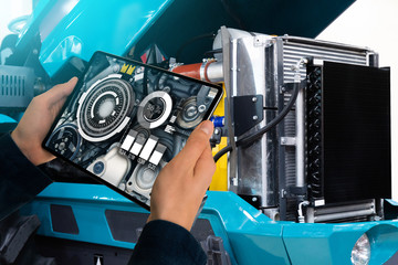 Serviceman repairing a tractor using augmented reality application.