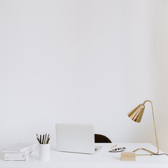 Office with laptop, lamp, notebooks. White work study cabinet workspace.