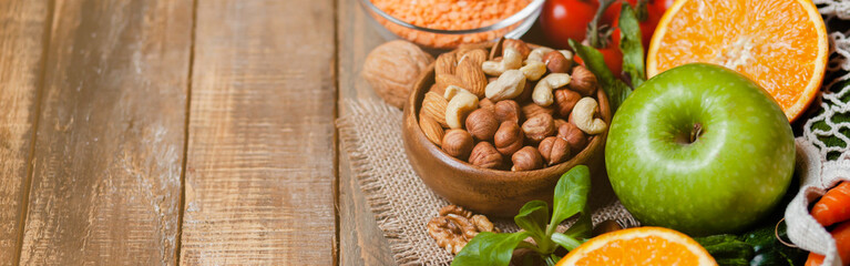 Fototapeta premium Concept of healthy vegan food, clean eating. Fresh raw ingredients on wooden background: vegetables, fruits, nuts, beans and lentils. No plastic, eco-friendly shopping, zero waste. Banner, copy space