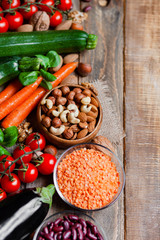 Concept of healthy vegan food, clean eating. Fresh raw ingredients,  wooden background: vegetables, nuts, beans, lentils. Ripe seasonal product for clean meal. Flat lay, top view, copy space for text.