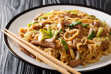 Stir-fried Shanghai noodles with napa cabbage, green onions and pork closeup in a plate. horizontal