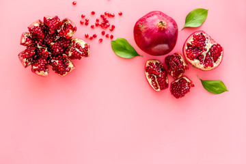 Ripe pomegranate fruit near leaf on pink background top-down copy space