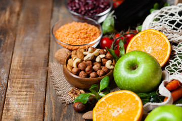 Concept of healthy vegan food, clean eating. Fresh raw ingredients on wooden background: vegerables, fruits, nuts, beans and lentils. No plastic, eco-friendly shopping for zero waste. Copy space