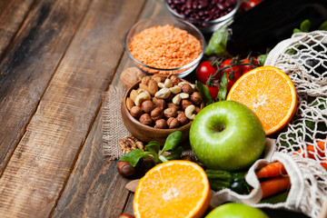 Concept of healthy vegan food, clean eating. Fresh raw ingredients on wooden background: vegetables, fruits, nuts, beans and lentils. No plastic, eco-friendly shopping for zero waste. Copy space
