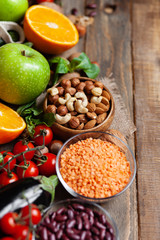 Concept of healthy vegan food, clean eating. On wooden background: vegetables, fruits, nuts, beans, lentils. Ripe seasonal product for clean meal. Copy space for text