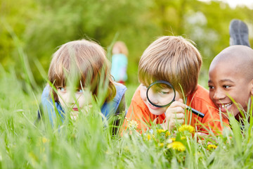 Drei Kinder erforschen Natur mit der Lupe