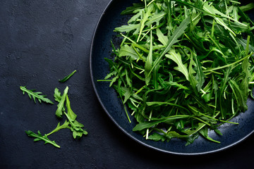 Fresh organic arugula in a black bowl. Top view with copy space.