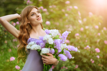 Portrait of beautiful young woman posing with lilacs