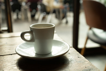 Cup of coffee in a nice hipster cafe. Soft focused image. Cup of espresso on old table of cafeteria. 