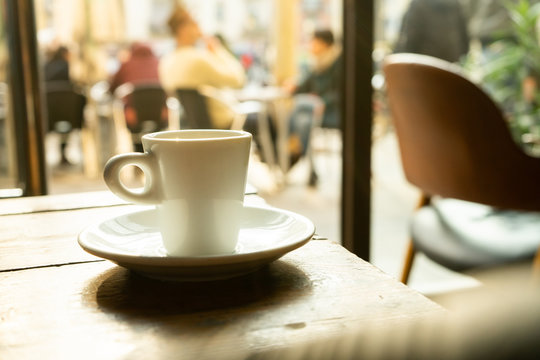 Cup of coffee in a nice hipster cafe. Soft focused image. Cup of espresso on old table of cafeteria. 