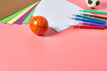 Multi colored felt pens, white blank paper sheet for drawing and toy balls lies on pink desk in kindergarten. Сoncept of parenting and education of children. Copy space