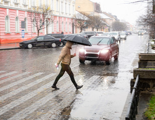 Busy city street people on zebra crossing in a rainy day. Dangerous situation. Defocused image