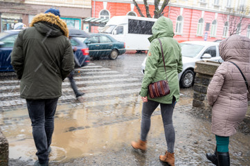 Busy city street people on zebra crossing in a rainy day. Dangerous situation. Defocused image