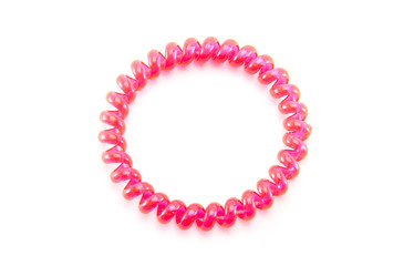 One pink spiral elastic for hair on a white isolated background. A flexible plastic item for a female hairstyle or an arm bracelet. Elastic accessory