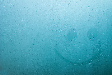 emoticon painted on glass window with drops background