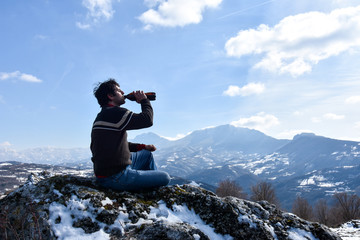 Tourist man drink beer and  feeling free on the top of the mountain. Climber enjoy in mountains in...