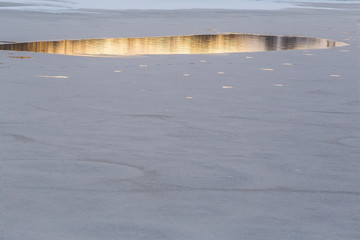 Big ravine in spring ice. Melting ice on the river. Sunlight is reflected in the water. dangerous spring ice.