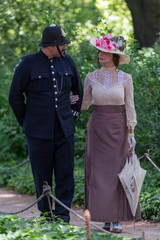 Elegant lady, from the high society of the twentieth century, walking with a British policeman in a...