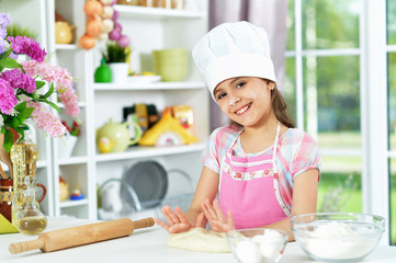 Cute girl making dough in the kitchen