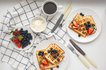 Beautiful breakfast: Viennese Belgian waffles decorated with berries, a plate with strawberries and blueberries