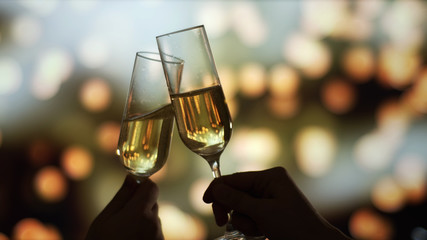 Couple clinks with glasses of champagne on New Year's Eve. Fireworks, Bokeh
