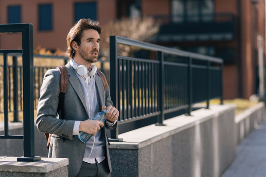 Young Businessman With Bottle Of Water Walking In The City.