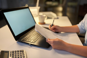 business, deadline and technology concept - businesswoman with papers and computer working at night office