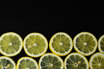  ten slices of lemon close-up on the bottom tap on a black background