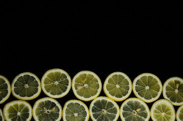  twelve circles of yellow lemon on the bottom edge on a black background