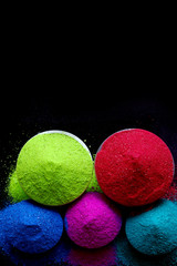 top view of colorful holi powder in bowls isolated on dark background. Space for text.