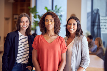 Portrait Of Three Businesswomen Standing In Modern Open Plan Office Together