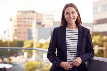 Portrait Of Smiling Businesswoman Standing Outside Office Building With City Skyline In Background