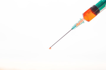 Syringe with a drop of blood at the end of the needle.