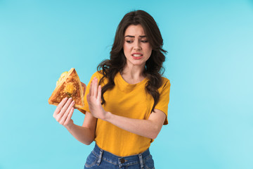 Beautiful woman holding sandwich showing stop gesture.