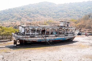 Old, weathered abandoned boat sits in a marsh at low tide on Elephanta Island in Mumbi, India