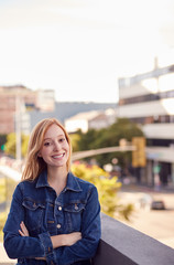 Fototapeta premium Portrait Of Smiling Young Businesswoman Standing Outside Office Building With City Skyline Behind