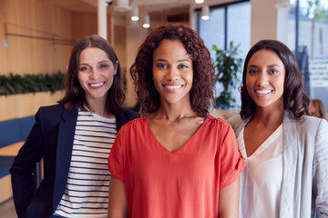 Portrait Of Three Businesswomen Standing In Modern Open Plan Office Together