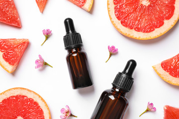 Flat lay composition with bottles of citrus essential oil on white background