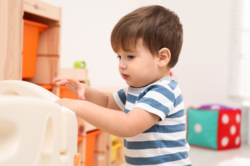 Cute little child playing in modern playpen at home