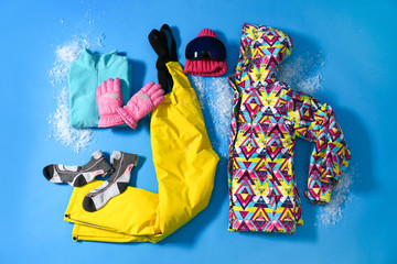 Stylish winter sport clothes on light blue background, flat lay