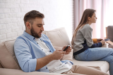 Couple addicted to smartphones ignoring each other at home. Relationship problems