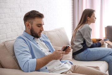 Obraz premium Couple addicted to smartphones ignoring each other at home. Relationship problems